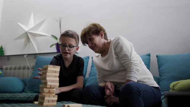 Grandmother and Grandson Play a Building Block Tower Game Together on Christmas. Family Bonds over the Holidays.