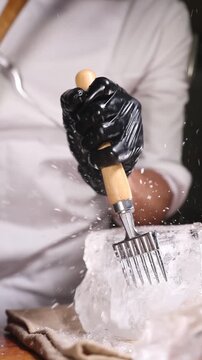 Barman partiendo un gran bloque de hielo con martillo y picahielos. Barman profesional rompiendo un gran bloque de hielo con martillo y picahielos. C&oacute;ctel artesanal, t&eacute;cnica artesanal.