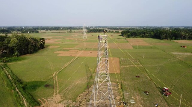 Aerial View of High Voltage Transmission Tower and Power Lines Across Farmland. teel Power Pylon Line Stretching Across Green Meadows.