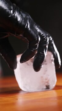 Barman preparando un cubito de hielo a mano. Barman profesional dando forma a un cubito de hielo con sus propias manos. C&oacute;ctel artesanal, preparaci&oacute;n de hielo artesanal.