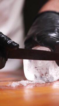 Barman tallando y dando forma a un cubo de hielo para c&oacute;ctel. Barman profesional cortando y perfilando un cubo de hielo a mano. C&oacute;ctel artesanal, t&eacute;cnica de tallado de hielo artesanal.