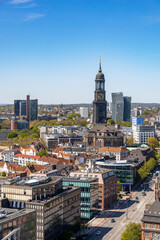 Obraz premium Aerial view of Hamburg, Germany, showcasing historic architecture and modern buildings from the St. Nikolai spire under a clear blue sky.