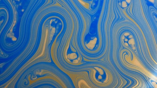 Abstract swirling blue and gold iridescent patterns on liquid surface