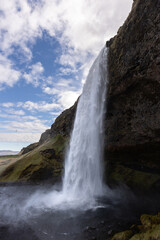 Obraz premium Cascade majestueuse tombant d’une falaise dans un paysage naturel islandais. Islande, Seljalandsfoss
