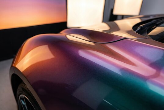 Close-up of a car's fender with iridescent paint reflecting ambient light