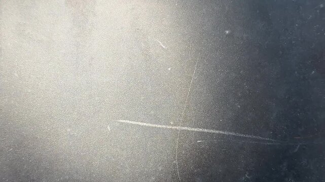 Wide view of a dark scratched dusty surface with soft diffused light from the upper area creating a gradual transition from light to deep shadow