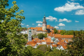 Obraz premium Cesky Krumlov Fortress Nestled Among Rich Green Foliage And Historic Rooftops