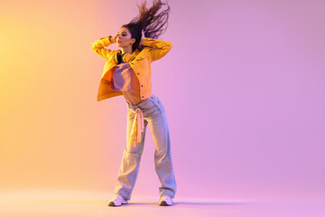 Obraz premium Young woman performing hip-hop dance on color background, space for text