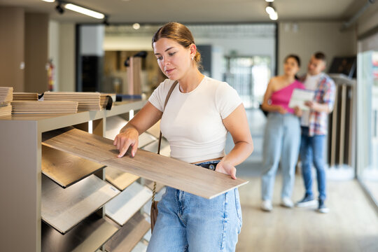 Female buyer chooses laminate flooring in a hardware store