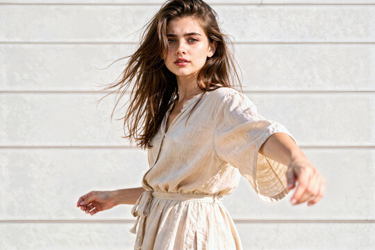 A beautiful young woman extending an arm wearing a simple dress