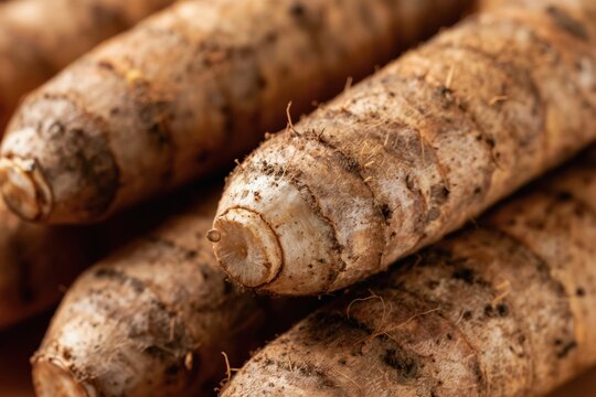 Heap of fresh raw yams with dirt still on them. Edible tubers are brown, earthy, and cylindrical. Natural food for healthy diets and organic cooking.