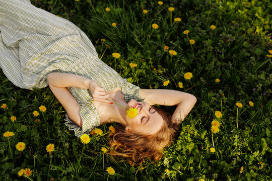 Woman Relaxing Outdoors Surrounded by Dandelions in Spring
