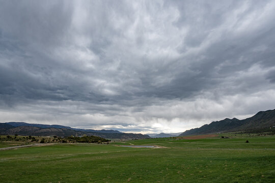 Much needed rain over agricultural fields of Grass Valley in Garfield County in western Colorado under developing storm clouds.