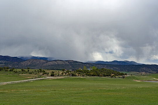 Much needed rain over agricultural fields of Grass Valley in Garfield County in western Colorado under developing storm clouds.