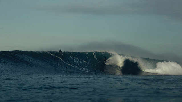 surfer taking off on large wave at sunrise