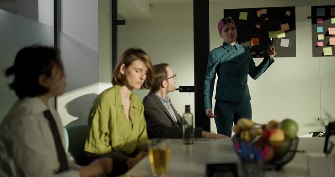 Team members discuss ideas with a businesswoman leading a meeting in a modern office setting during early afternoon hours