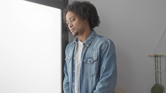 Woman placing hand on man's chest in studio softbox light, hand touching denim jacket with ring visible; intimacy tenderness comfort.