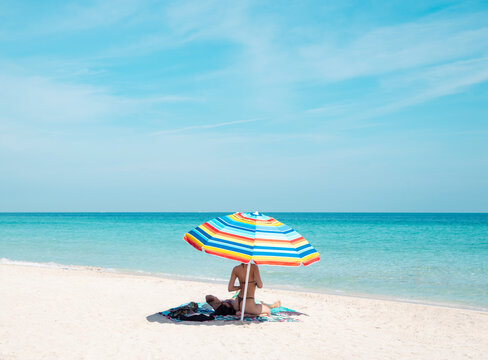 bikini woman on beach towel with colorful umbrella in miami florida