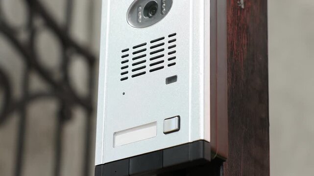Modern intercom system on gate outdoors, closeup. Camera moving up