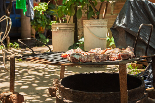 Hombre preparando parrilla para asado argentino en patio exterior durante reuni&oacute;n de fin de semana