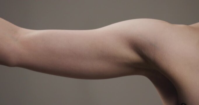 Close-up view of a slender female arm bending her elbow in neutral tones