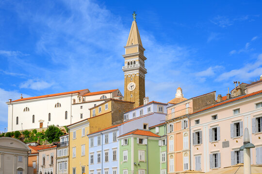 The bell tower of St. George's Parish Church rises above the pastel colored buildings in Tartini Square, or Tartinijev Trg, in the seaside town of Piran, Slovenia, on the Istrian Peninsula.