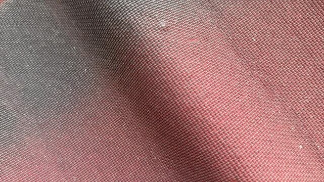Closeup red corrugated roof texture showing sunlit waves, subtle paint stains, fabric like grain and shadowed ridges, roofer