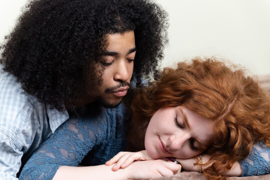 Loving partner watching redhead woman sleeping peacefully in close embrace
