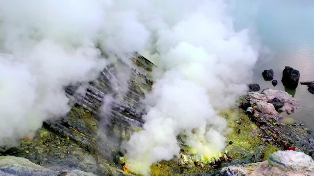 Active Volcano Crater of Mount Ijen with Smoke and Yellow Mineral. Documentary Style Drone Shot of Nature Ceramic Pipes Used For Sulfur Extraction Inside Deposits In East Java Indonesia for Work 4k