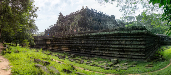 Fototapeta premium Tourists explore the ancient Baphuon temple, a 11th-century Khmer architectural marvel, at Angkor Archaeological Park in Siem Reap, Cambodia.