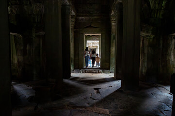 Fototapeta premium A tourist explores the ancient stone corridors of Preah Khan Temple, Angkor Wat in Siem Reap, Cambodia. The temple complex is a UNESCO World Heritage site and a popular destination for visitors.
