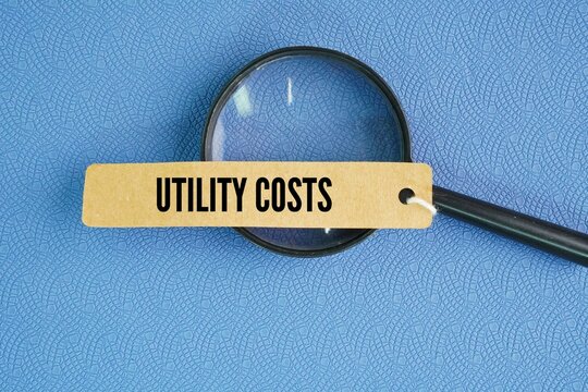 Magnifying glass and paper tag with the word utility costs. monthly or yearly expenses required to operate and maintain a home or business, primarily covering essential services like electricity