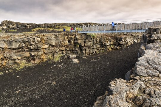 Tourists on bridge over continental divide, Mid-Atlantic Ridge, volcanic landscape, Reykjanes Peninsula, near Reykjavik, Iceland
