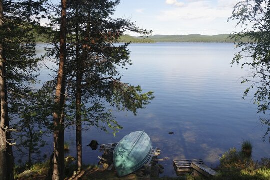 Small boat lying on a deserted lake, trees, summer, Lapland, Inari, Finland