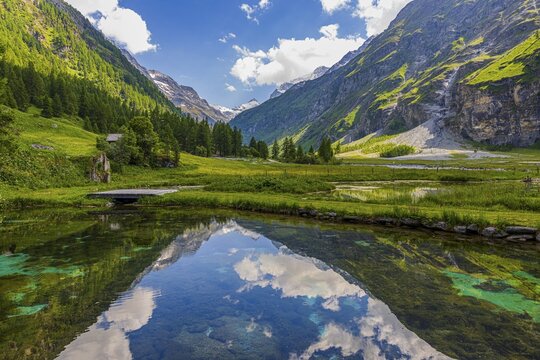Mountains and clouds reflected in a pond, near Relais Tzoucdana, Zinal, Val d'Anniviers, Valais Alps, Canton Valais, Switzerland