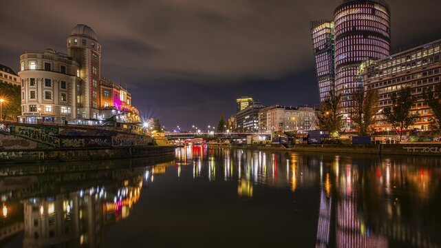 Lights reflected in the Danube Canal, on the left the Urania observatory, on the right illuminated office towers, night shot, Vienna, Austria