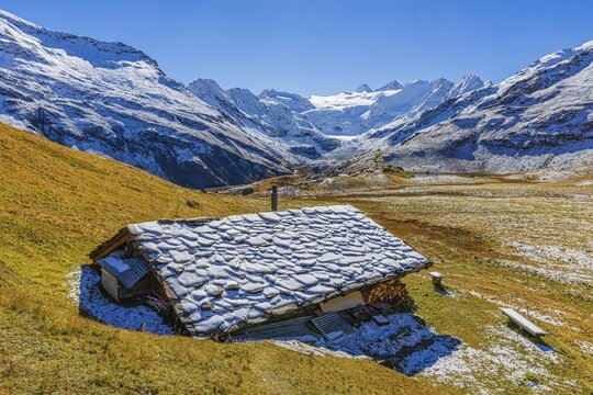 Alpine hut with snow-covered roof, slightly snow-covered alpine meadow, behind the Moiry glacier, near Grimentz, Val d'Anniviers, Valais Alps, Canton Valais, Switzerland