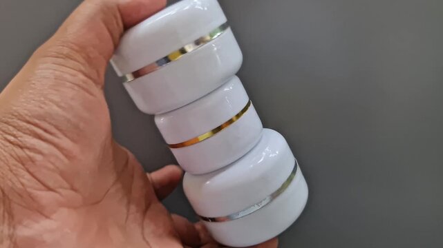 Sidoarjo, Indonesia - 24 May , 2026: Blank White Cosmetic Cream Jar Mockups with Gold and Silver Trim, Unbranded Skincare Packaging on Minimalist Grey Background