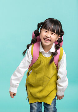 A cheerful Asian female student, with her hair in gourd braids and carrying a pink backpack, stands against a blue-green background with a back-to-school theme.