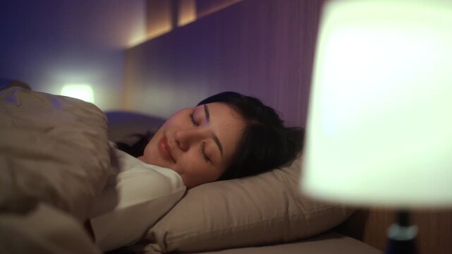 Young woman sleeping peacefully in comfortable bed at home. Sleep well, sweet dreams, deep sleep, relaxation, healthy lifestyle, wellness and bedtime comfort concept.

