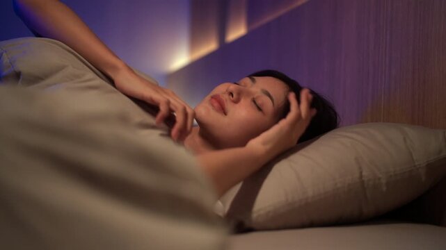 Young woman sleeping peacefully in comfortable bed at home. Sleep well, sweet dreams, deep sleep, relaxation, healthy lifestyle, wellness and bedtime comfort concept.
