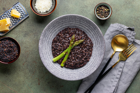 Black rice risotto with asparagus in ceramic bowl. Italian Cuisine. Top view