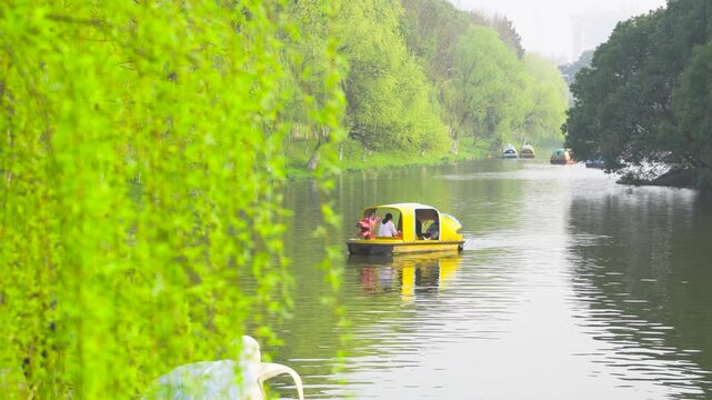 People riding a yellow dragonshaped pedal boat on a calm park river