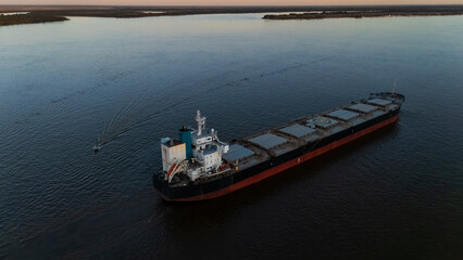 Aerial view of large cargo ship navigating Parana river at sunset near Rosario, Argentina, commercial shipping and grain transport on waterway © simonmayer