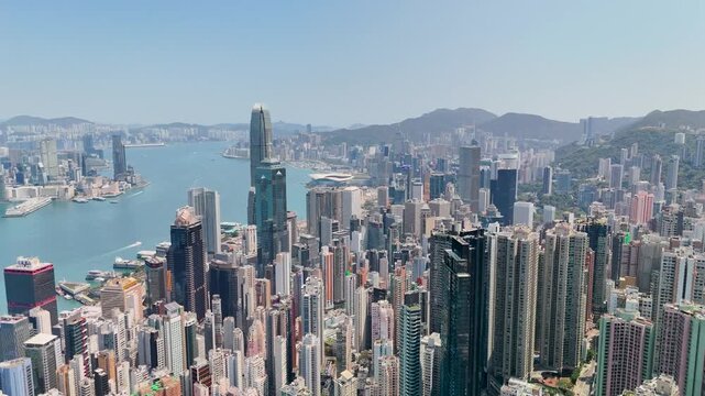 Aerial panoramic top view of forest peak slope and view of highrise skyscrapers of Hong Kong city.