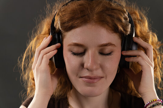 Young woman closing eyes, listening to music, finding peace and mindfulness