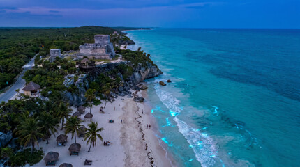 Fototapeta premium Majestic Mayan ruins of Tulum perched on a cliff overlooking the turquoise Caribbean Sea at sunset.