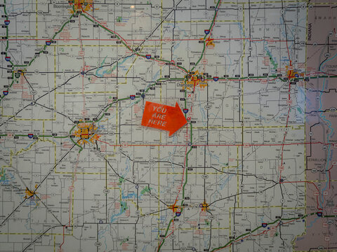 Road map of Central Illinois displaying Decatur and Champaign with a vibrant orange plastic arrow pointing to the text You Are Here