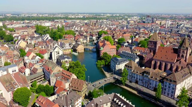 Strasbourg, France. The Grande-Ile historic core, its dense terracotta rooftops and Gothic cathedral spire rising above the Ill River, Drone footage under clear summer sky. Drone footage, Departure o