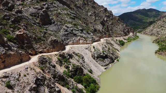 Aerial perspective flying through the deep Dark Canyon in Kemaliye, Turkey. Drone shot following the path of the Karasu River with the legendary hand-carved Stone Road visible on the cliff